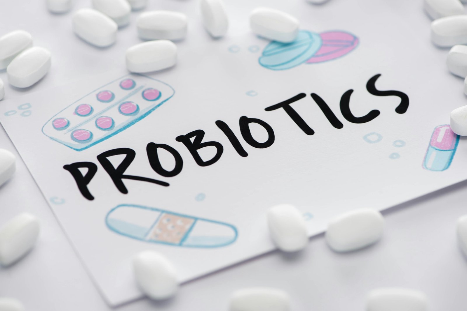 selective focus of drawing with probiotics lettering near pills on white background