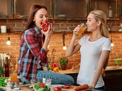 Eat well to be well Young female friends preparing together healthy meal in modern kitchen. Cozy